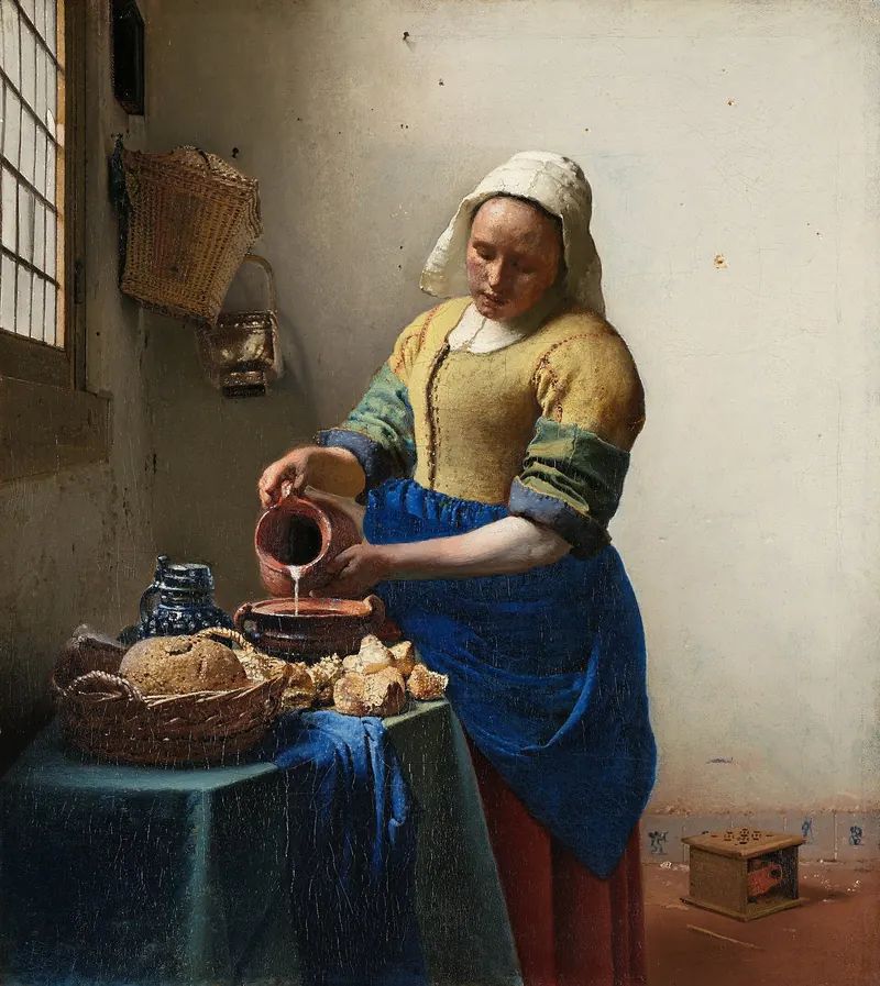 Het melkmeisje van Johannes Vermeer: een keukenmeid in geel jak en blauw schort schenkt bij het raam melk uit een kan in een kom; op tafel liggen brood en een mandje.